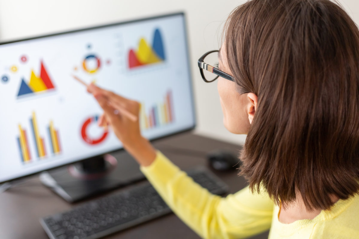 Image d'une femme regardant son ordinateur, avec des statistiques visibles à l'écran